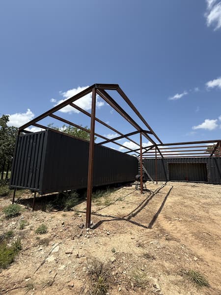 Steel roof structure framed over both shipping containers