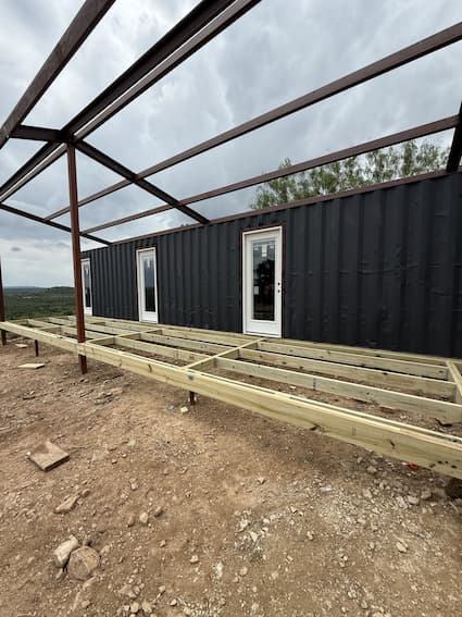 Containers with doors and windows installed and deck framing started
