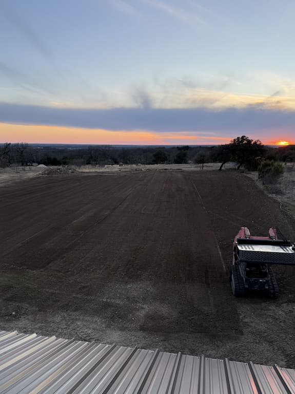 Graded arena ground at sunset before fencing
