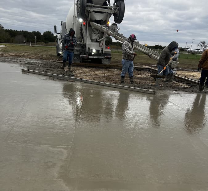 Freshly poured concrete driveway leading to a metal shop building