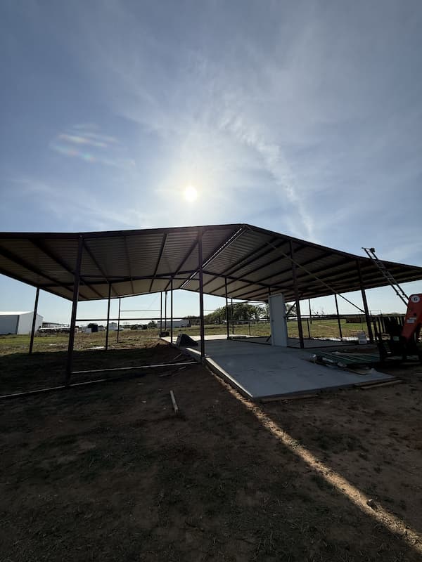 Barn frame with the roof panel installed, sun behind the structure