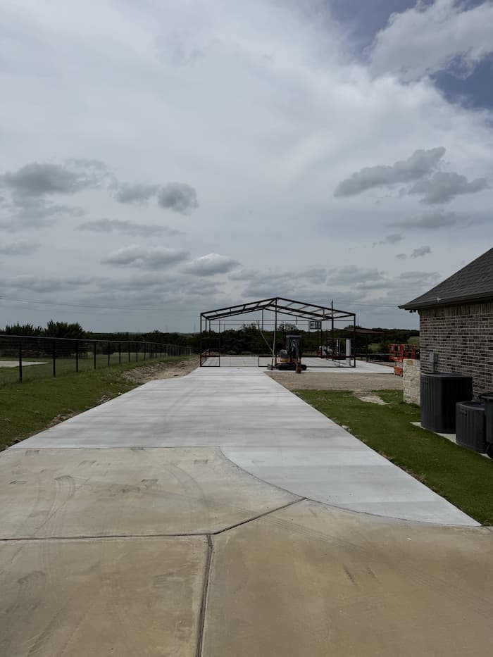 Steel frame and finished concrete drive leading to the building